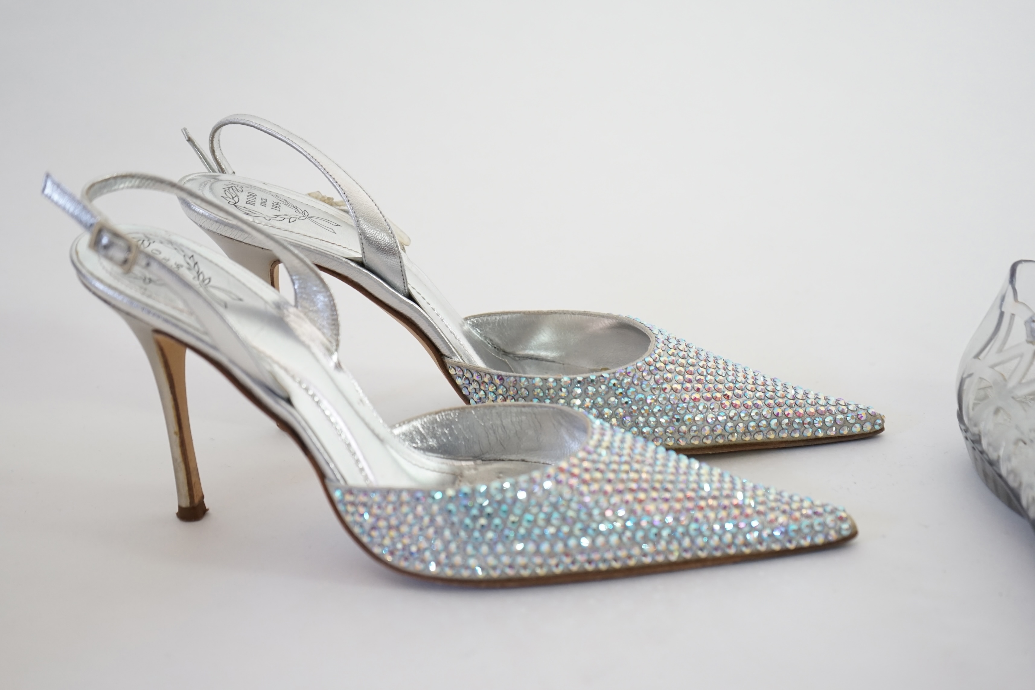 Three pairs of lady's silver shoes: Rodo silver diamonté sling back heels, Moda in Pelle silver snakeskin pattern heeled pumps and a pair of Stuart Weitzman clear jelly's with crystals. Size 38.5 (UK 4). Proceeds to Happ